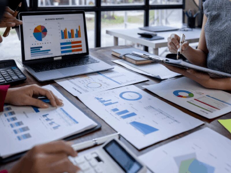People analyzing charts and graphs on table.