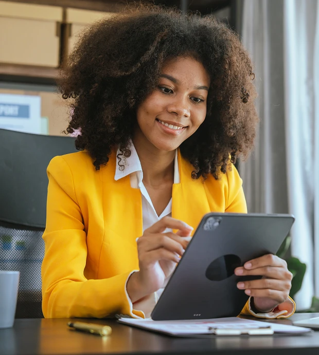 Woman in yellow blazer using a tablet.