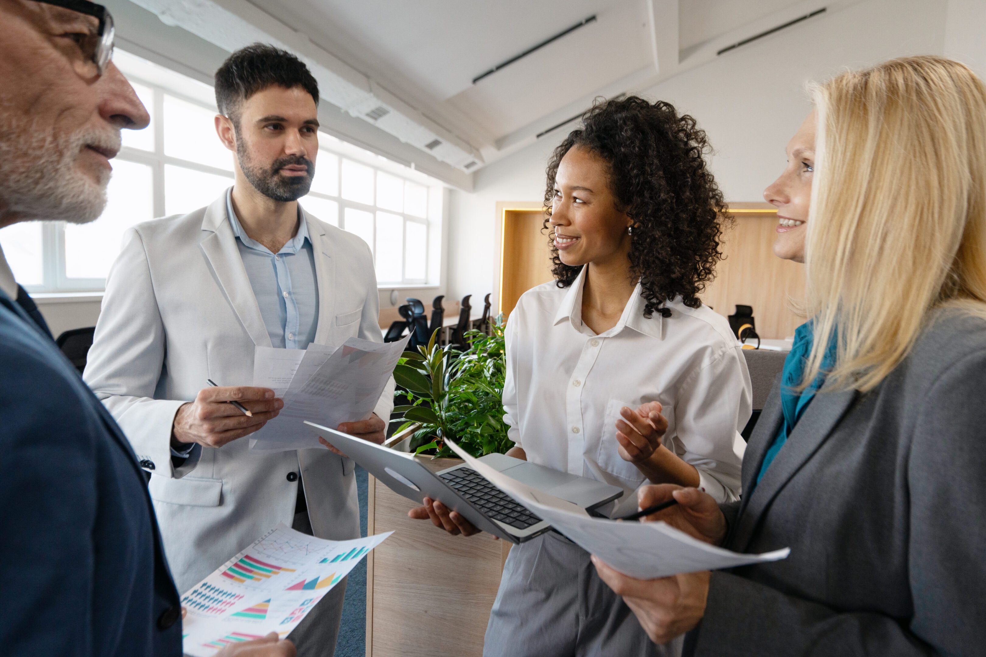 Diverse colleagues collaborating in a modern office, analyzing financial data and engaging in strategic planning during a productive meeting, exemplifying. Teamwork concept