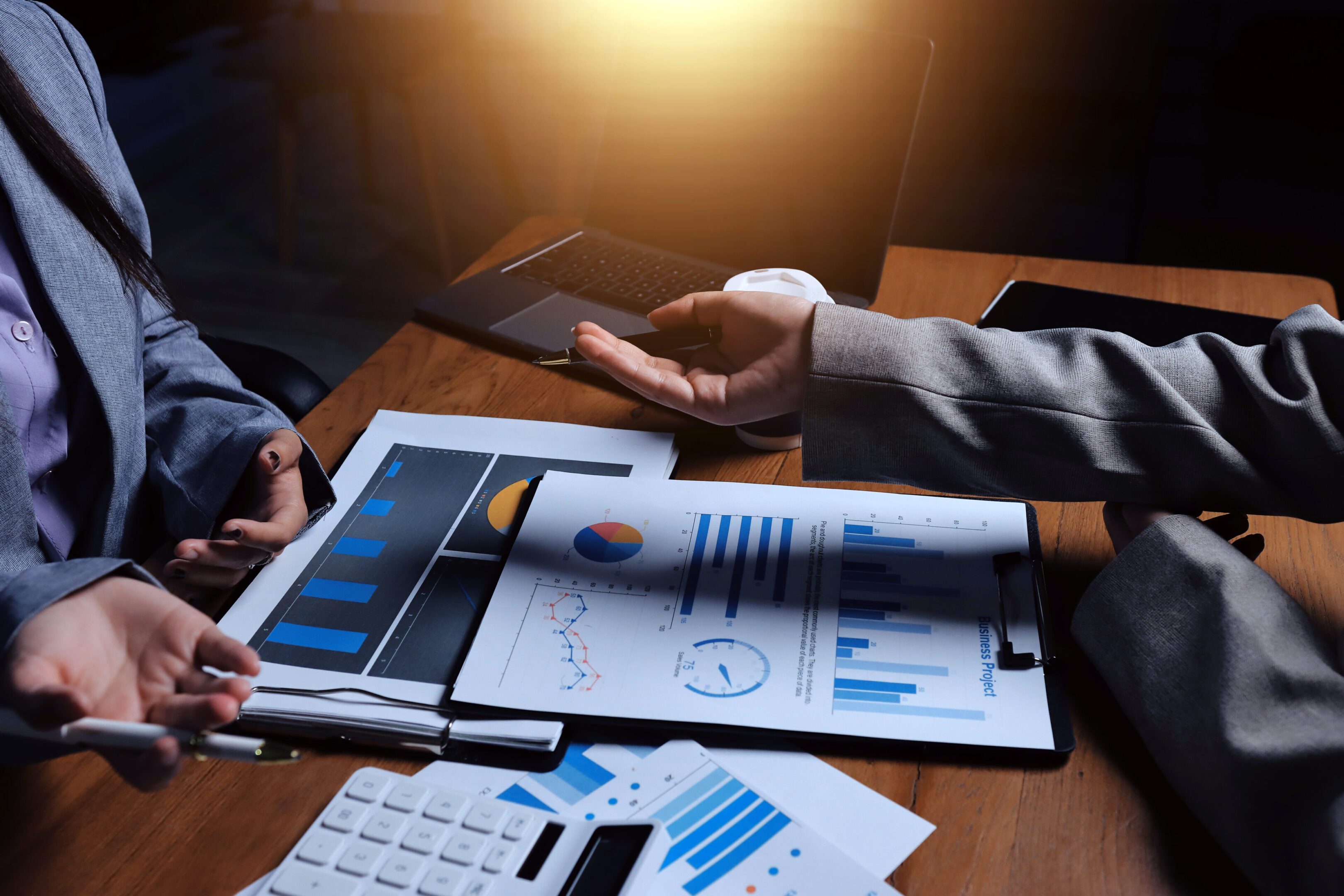 Group of confident business people point to graphs and charts to analyze market data, balance sheet, account, net profit to plan new sales strategies to increase production capacity.